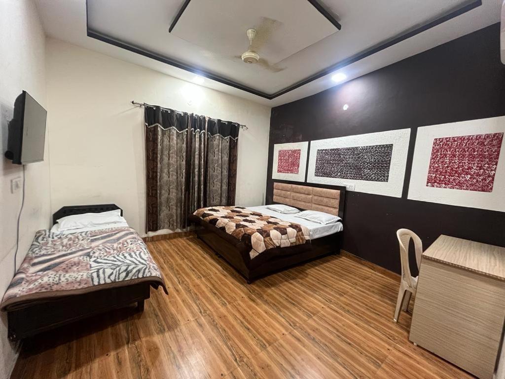 a room with two beds and a table and chairs at SHRI GANPATI GUEST HOUSE in Amritsar