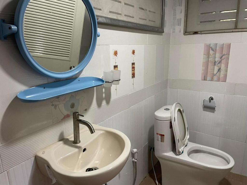 y baño con lavabo, espejo y aseo. en Srihome ยายศรีโฮมแอนแคมป์ปิ้ง en Ban Don Tum (1)