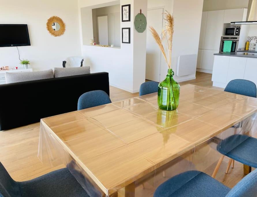 - une table en bois avec un vase vert dans le salon dans l'établissement Agréable T3 - 70m2 avec petite terrasse, à Granges-lès-Valence