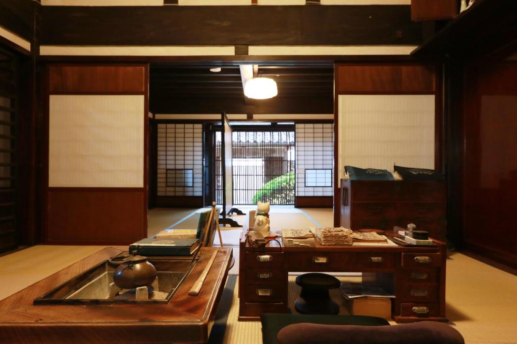 a living room with a table and a room with windows at 古民家一棟貸 太田邸 in Yazu
