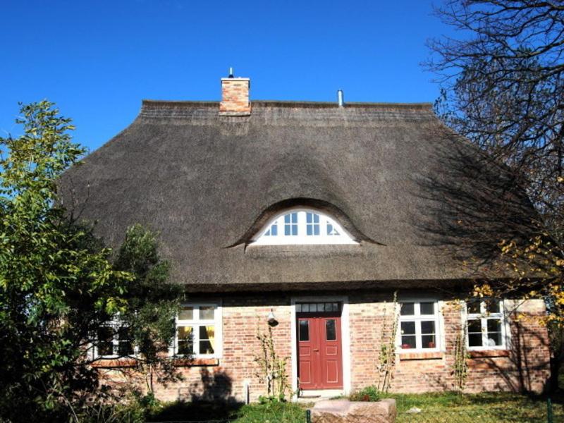 una casa con techo negro y puerta roja en Ferienwohnung Rügen in Putgarten, en Putgarten