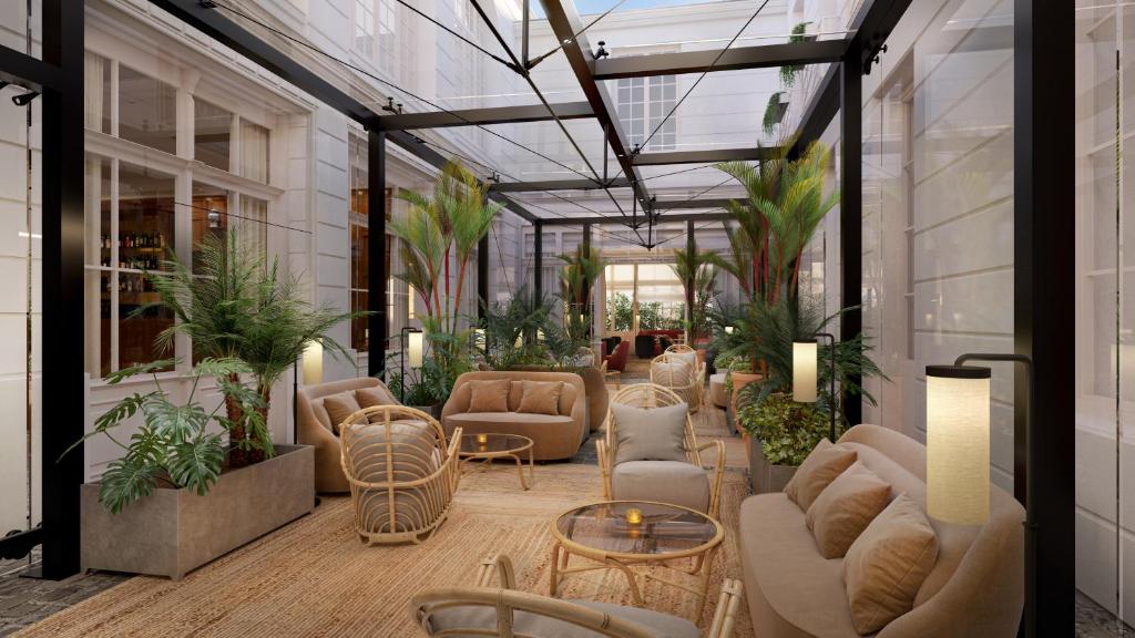 ベルサイユにあるHôtel Les Lumièresのソファ、テーブル、植物のあるコンサバトリー