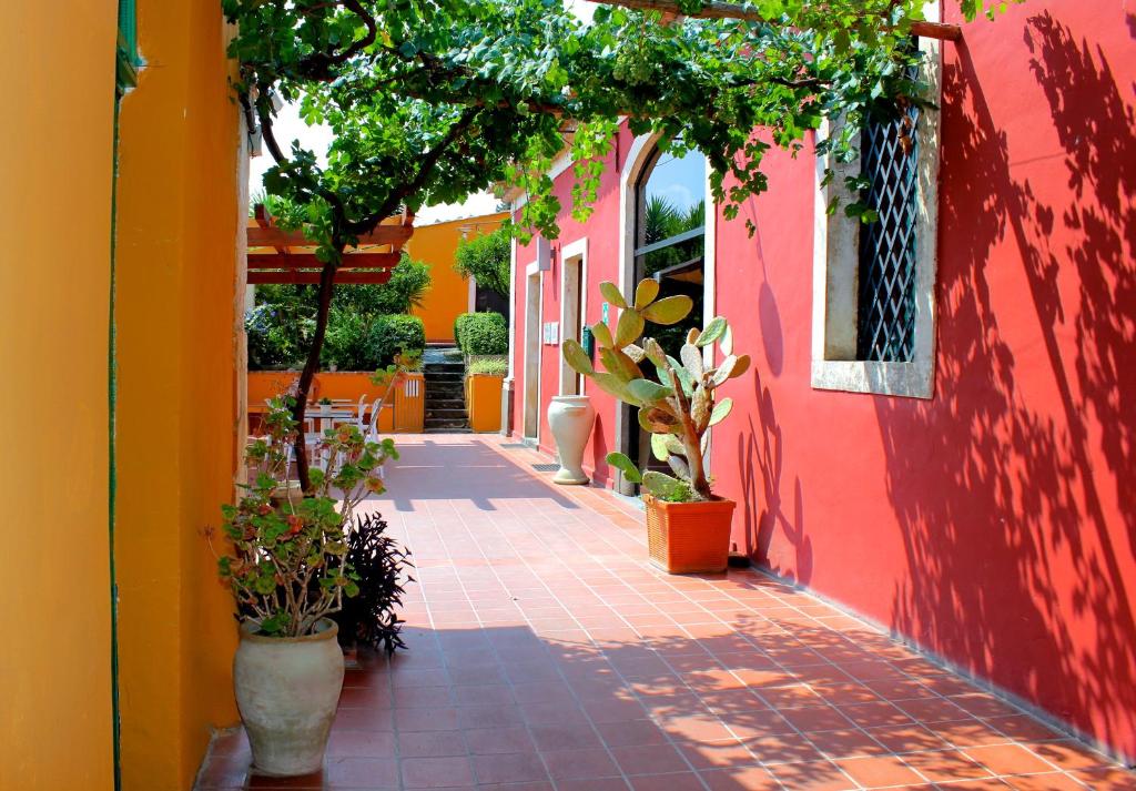 a red and yellow building with plants on a sidewalk at Agriturismo Roccadia in Carlentini