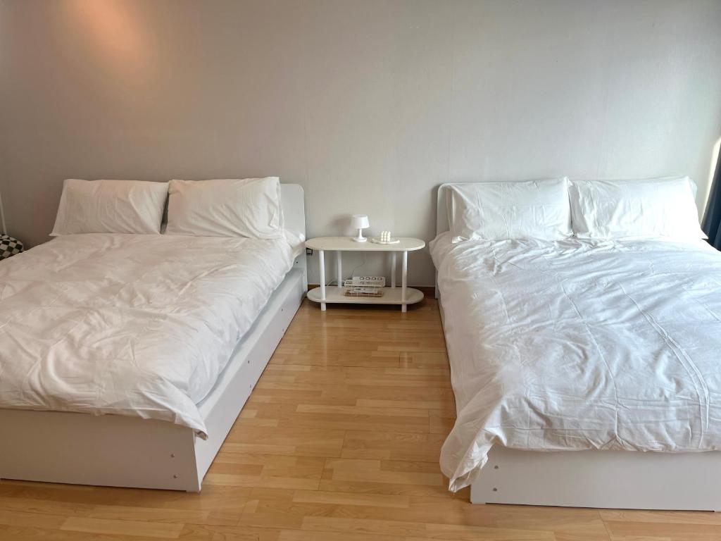 1 dormitorio con 2 camas con sábanas blancas y mesa en Hongik univ station Exit 1 en Seúl