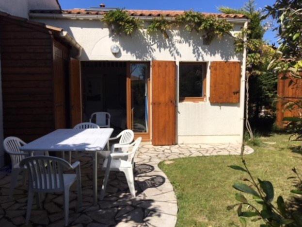 une terrasse avec une table et des chaises ainsi qu'une maison dans l'établissement Saint Palais sur Mer - MAISON MITOYENNE de VACANCES - VILLAS de CORDOUAN, à Puyraveau