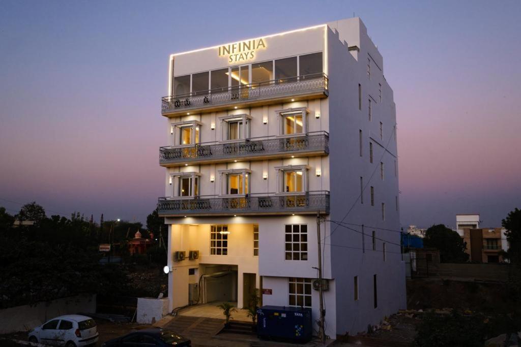 Infinia Stays - A Luxury Boutique Hotel في أودايبور: مبنى أبيض عليه لافتة