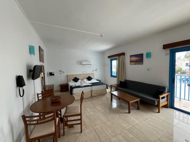 Kefalonitis Hotel Apartments في بافوس: غرفة معيشة مع أريكة وطاولة