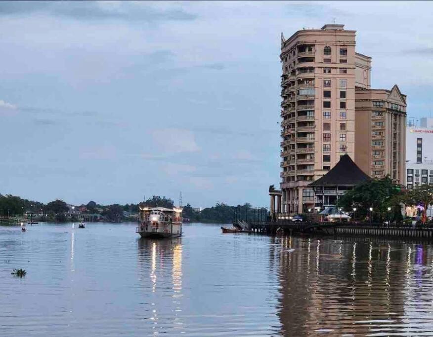 um barco num rio ao lado de um edifício alto em Riverbank Suite @ Waterfront KCH em Kuching