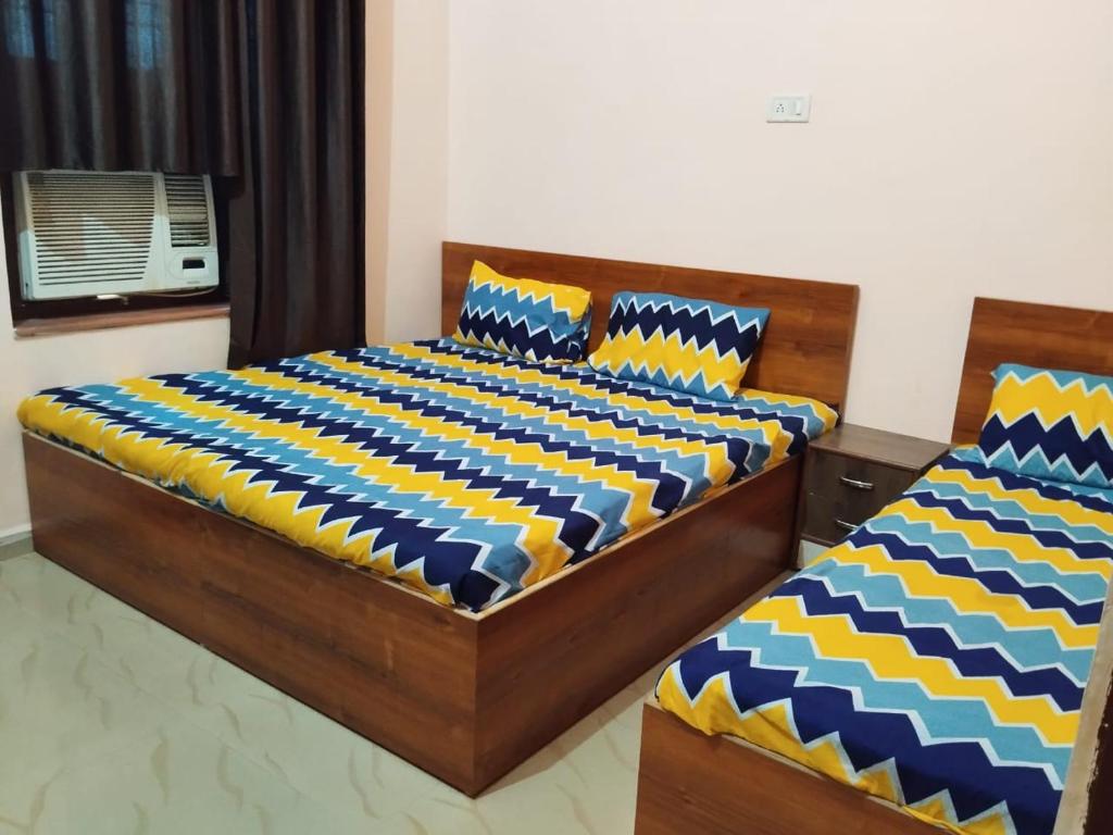 two beds in a bedroom with blue and yellow at Shiv Shakti Palace in Rīngas