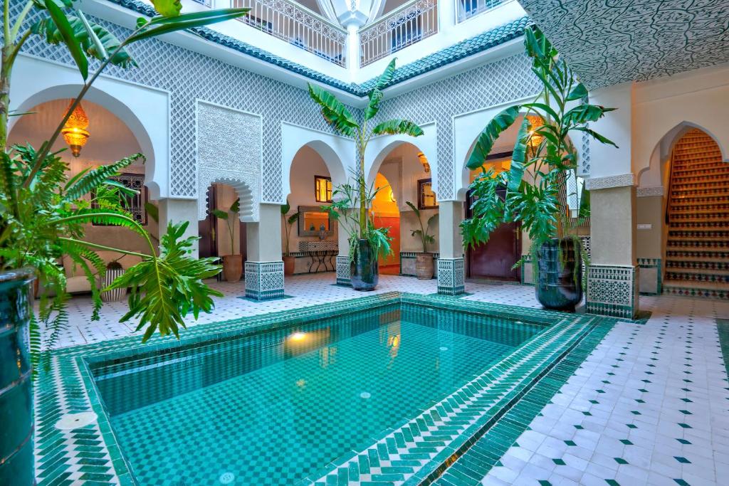 an indoor pool in a building with palm trees at BÔ Riad Boutique Hotel & Spa in Marrakech