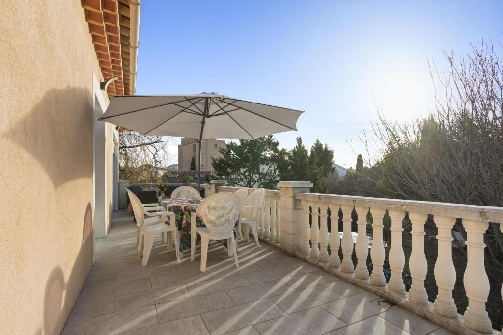 une table et des chaises avec un parasol sur un balcon dans l'établissement Maison Saint-Raphael - Les vignes, à Saint-Raphaël