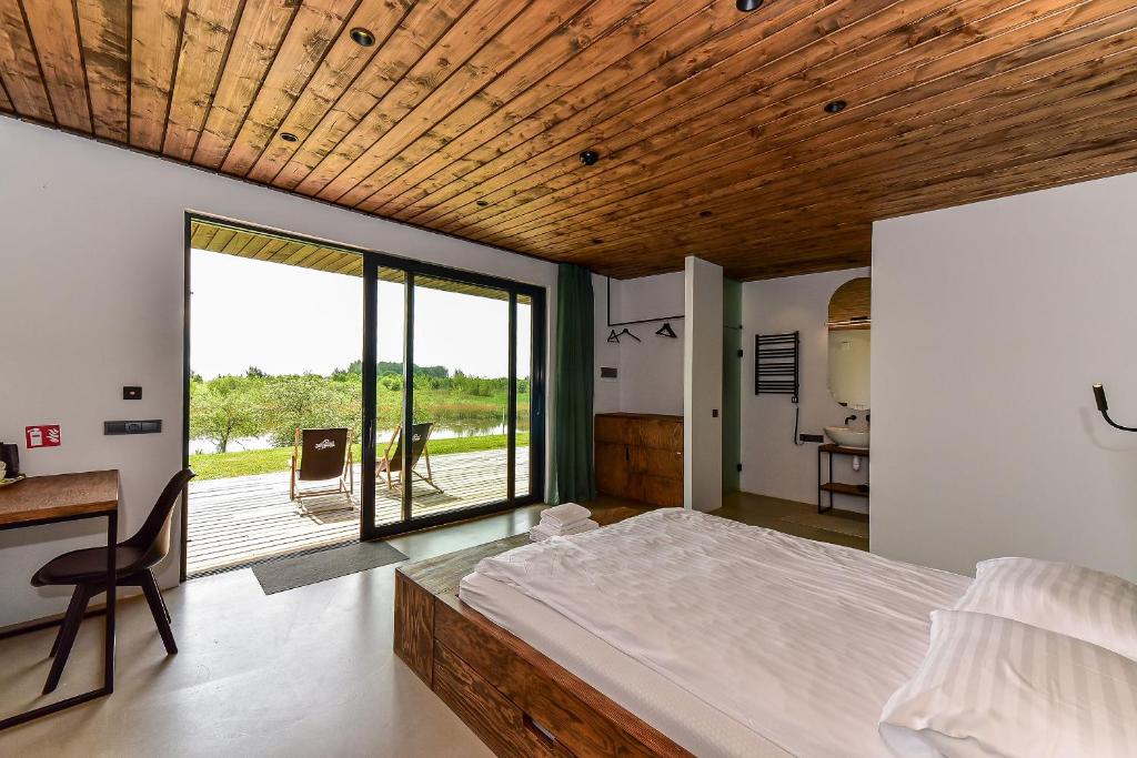 Schlafzimmer mit einem Bett, einem Schreibtisch und einem Fenster in der Unterkunft Wakepond atostogų slėnis in Anykščiai