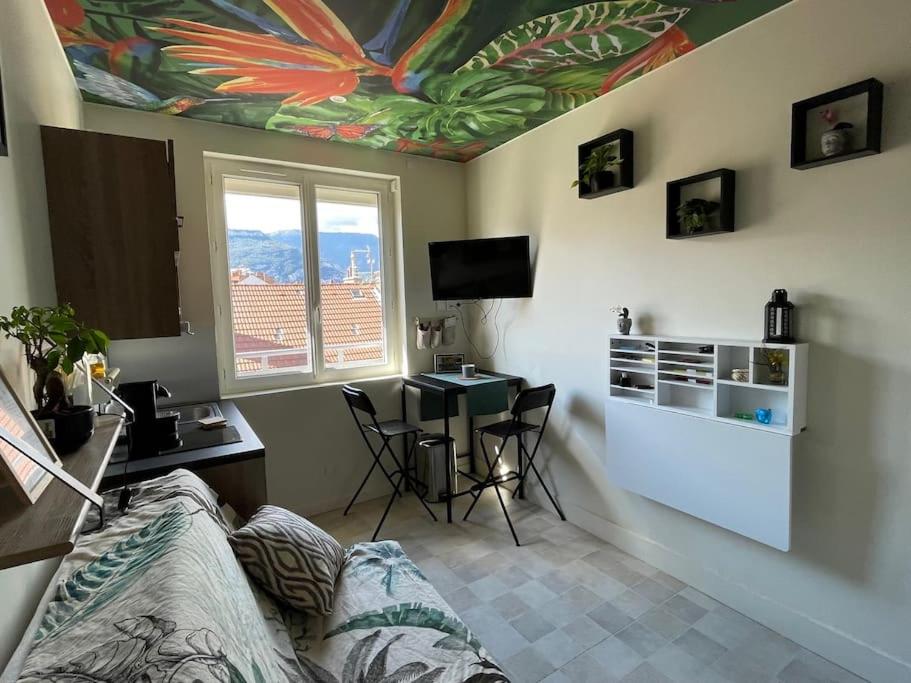 - un salon avec un canapé, une table et une fenêtre dans l'établissement St Bruno - Studio Tropiques , à Grenoble