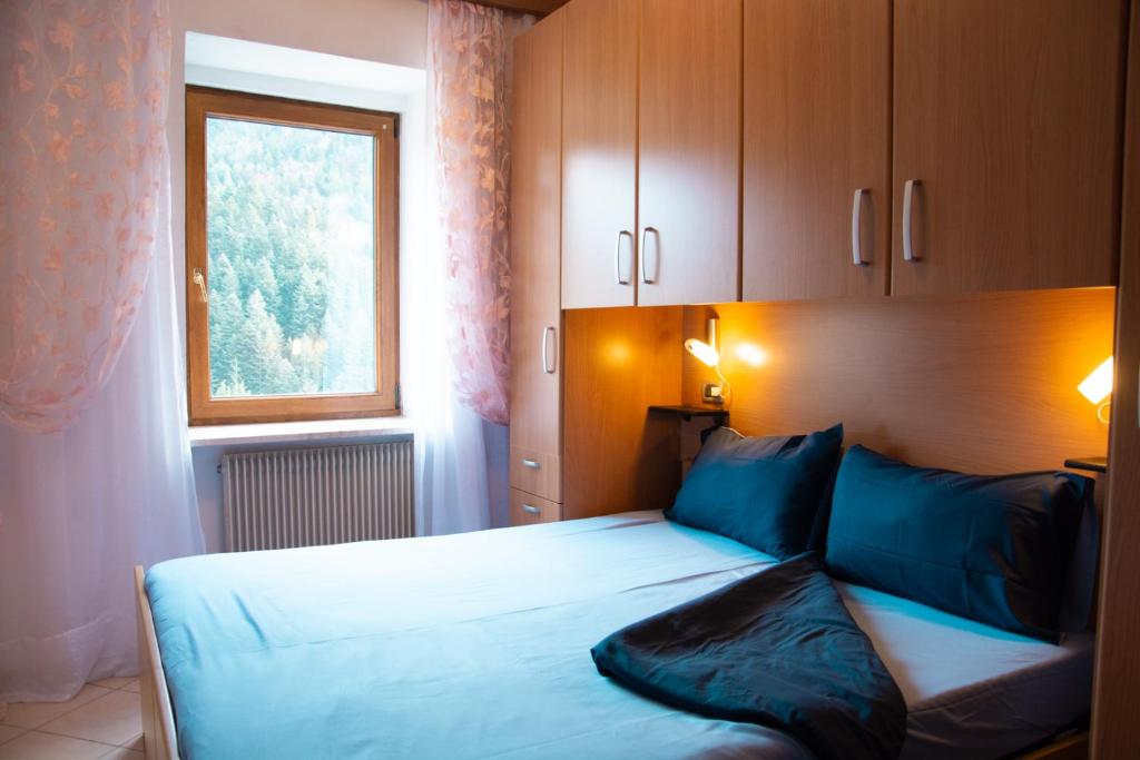 a bedroom with a bed with blue pillows and a window at Residenza Garibaldi in Molveno