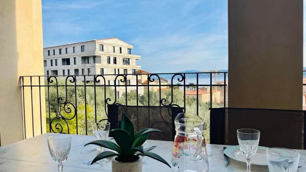 une table avec des verres et une plante sur un balcon dans l'établissement Appartement Les Oliviers L'ILE ROUSSE, à LʼÎle-Rousse