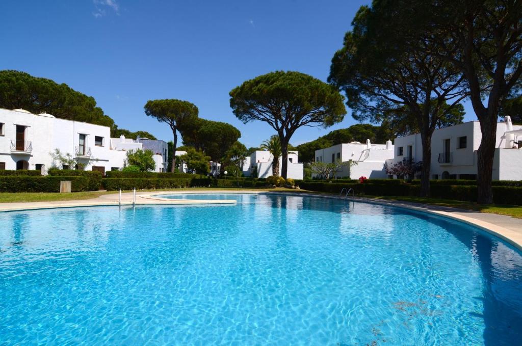 a large blue swimming pool with trees and white buildings at PIVERD DEL GOLF 75 in Pals