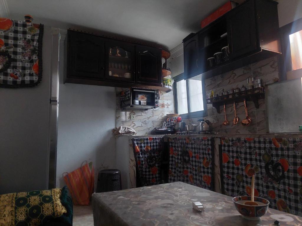 una cocina con armarios negros y una mesa. en imintanoute, en IminTanout