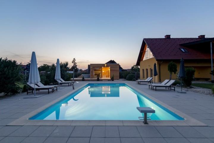una grande piscina con sedie e ombrelloni accanto a una casa di Vila Izabela a Križevci pri Ljutomeru