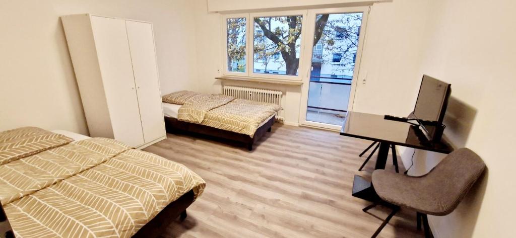 - une chambre avec 2 lits, une télévision et un bureau dans l'établissement Apartments EFDE GmbH Ferienwohnung, à Heilbronn