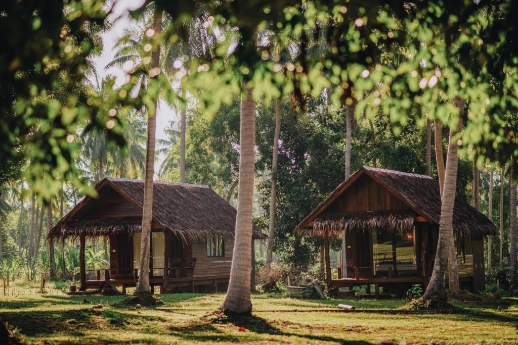 two bamboo huts in a forest with palm trees at COCO Canopy Boutique Resort in Ko Jum