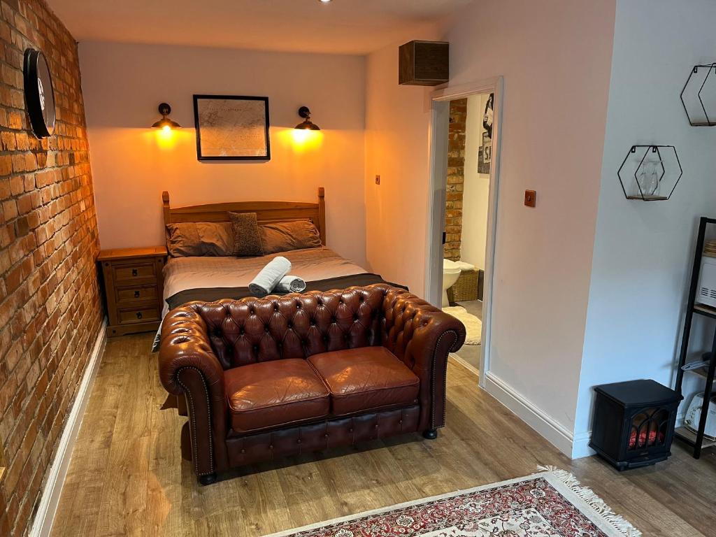 a bedroom with a leather couch and a bed at East Bridgford Coach House Inc Spa and Treatments in East Bridgford