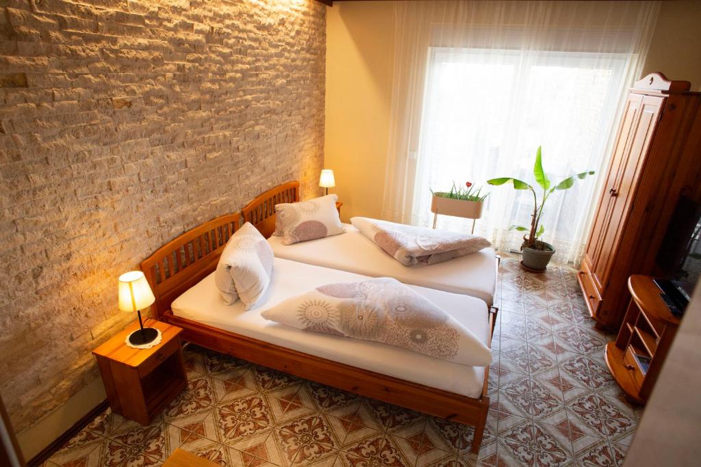 2 camas individuales en una habitación con una pared de ladrillo en Gästehaus Mariola, en Wulkaprodersdorf
