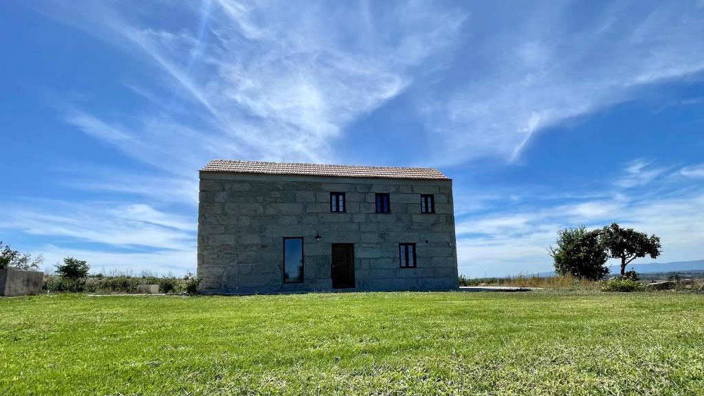 un pequeño edificio de piedra en un campo de césped en Quinta da Cumieira Nova, en Seia