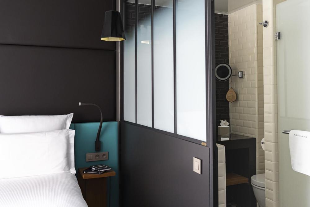 a bedroom with a bed and a door to a bathroom at Terrass&quot; Hotel in Paris