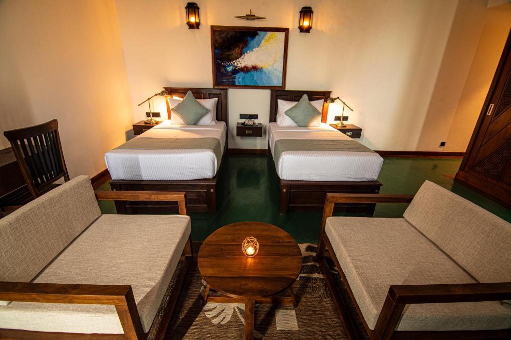 une chambre d'hôtel avec trois lits et un canapé dans l'établissement The Rockwall Boutique Hotel, à Bentota