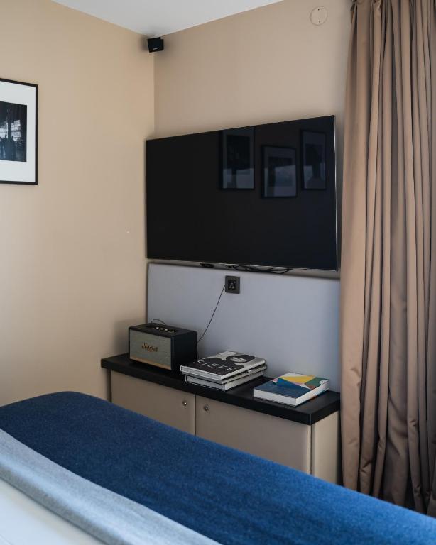 a bedroom with a bed with a tv on the wall at Terrass&quot; Hotel in Paris