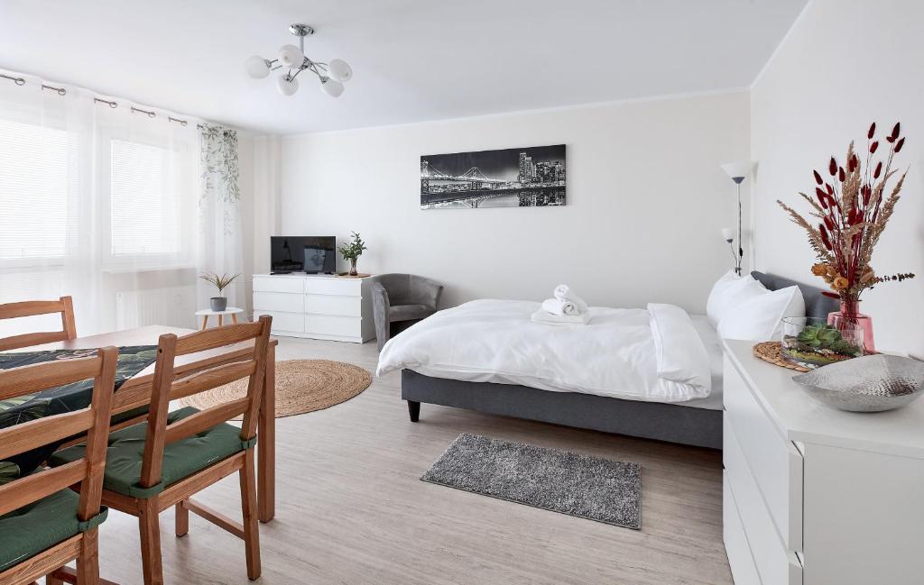 a white bedroom with a bed and a dining room at Osiedle Zwycięstwa Chic Studio in Poznań