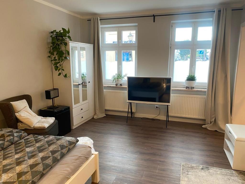 a living room with a tv and a couch and windows at Apartment 1 in Neuruppin