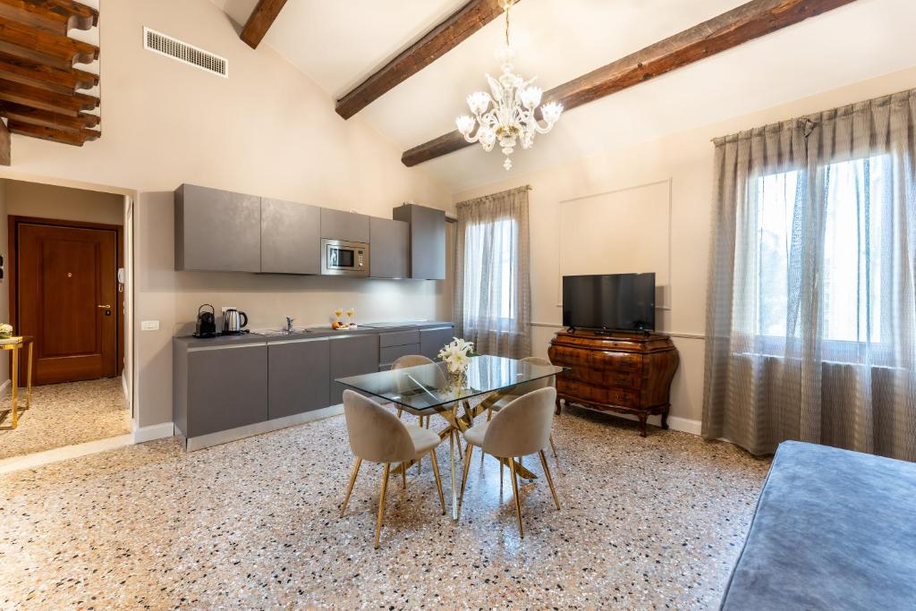 cocina y comedor con mesa de cristal y sillas en San Vio Palace Luxury Apartments, en Venecia