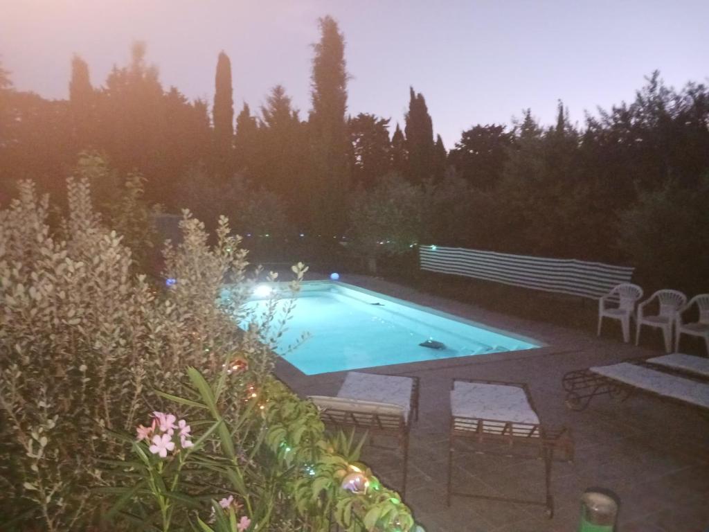 - une piscine dans une cour avec des chaises et des arbres dans l'établissement Gite ALPILLES & piscine - Oliveraie Bio Mas de Cargane, à Entressen