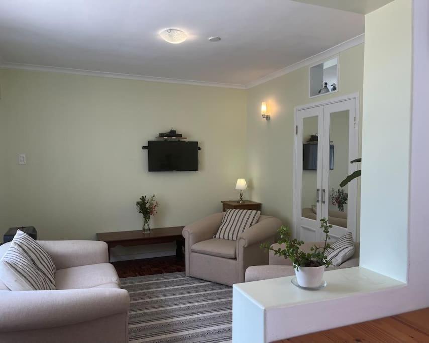 a living room with two chairs and a tv at Harbour Cottage Kalk Bay in Cape Town