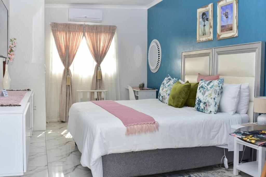 sypialnia z dużym łóżkiem z niebieskimi ścianami w obiekcie Villa Palesa Guesthouse w mieście Grahamstown