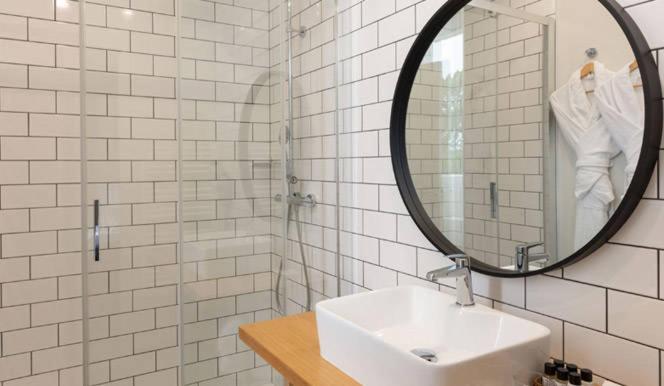 a white bathroom with a sink and a mirror at Hôtel Les Costans, The Originals Relais in Perros-Guirec