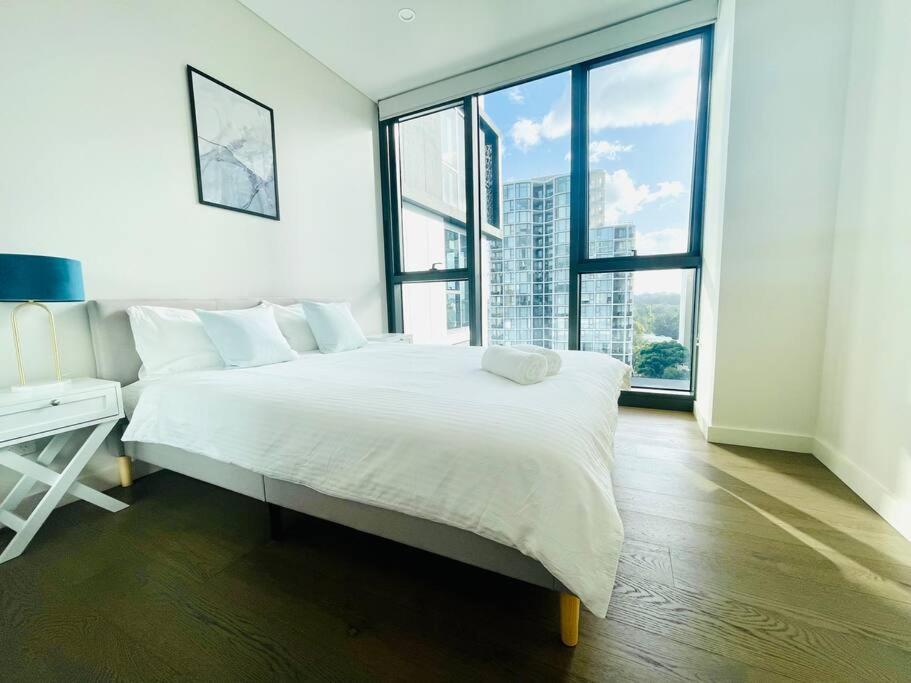 a white bedroom with a large bed and a window at Family Residence (3 Bedrooms, Pool, Gym, Parking) in Sydney