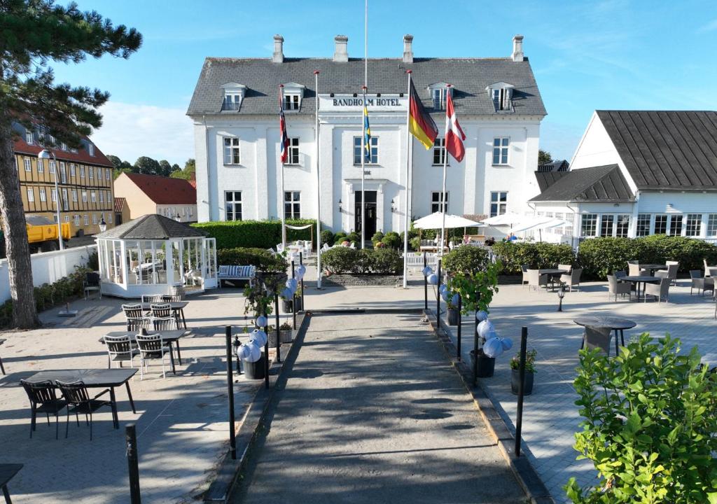 a large white building with tables and chairs in front of it at Bandholm Badehotel in Bandholm
