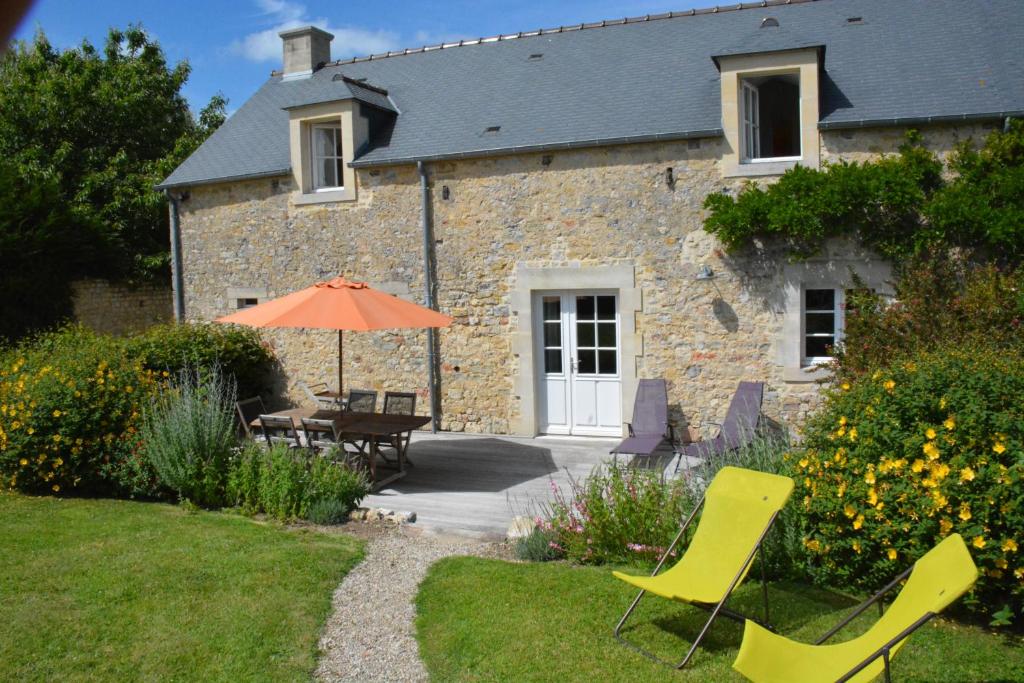 a stone house with a table and chairs and an umbrella at Les Chaufourniers / L'Ecurie in Crouay