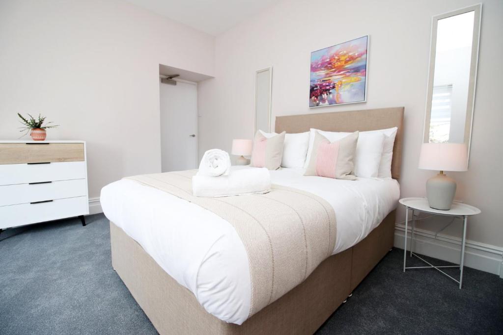 a white bedroom with a large bed with white pillows at Archer Road Penarth Free parking in Cardiff