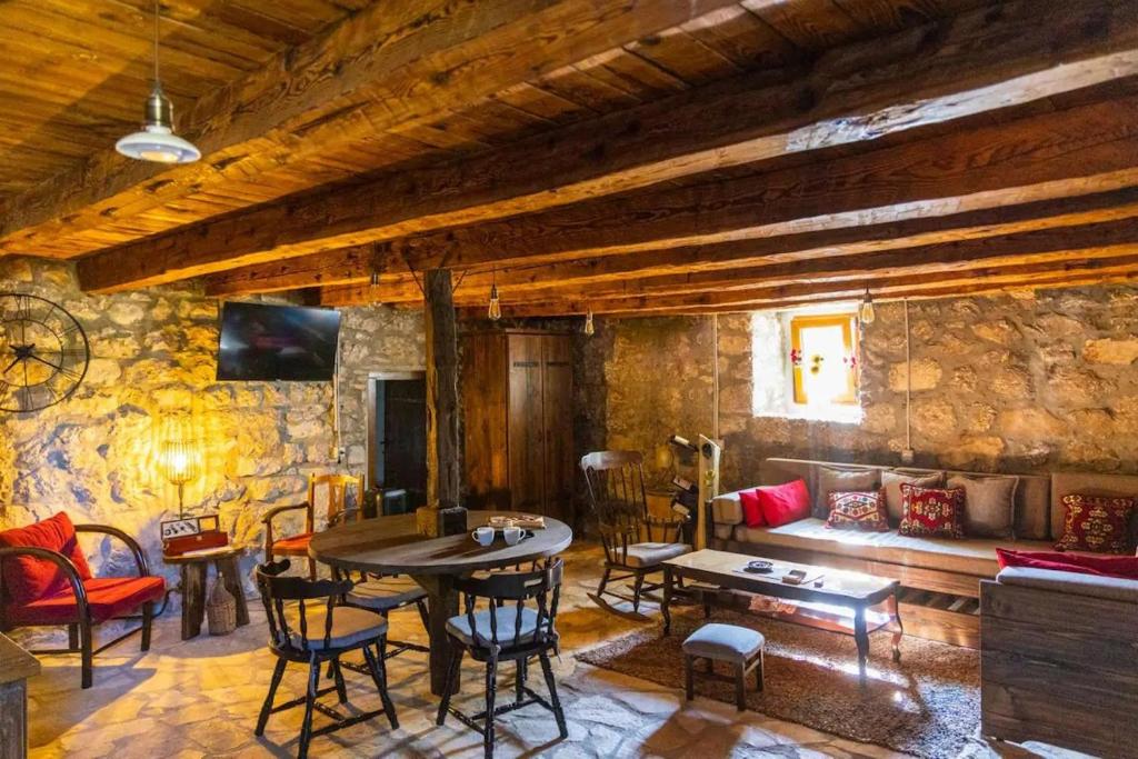 uma sala de estar com uma mesa e cadeiras e um sofá em Old House Piperi em Podgorica