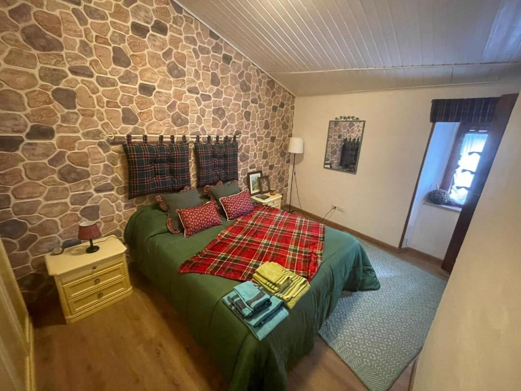 een slaapkamer met een groen bed en een stenen muur bij La casina in Voltaia in Piancastagnaio