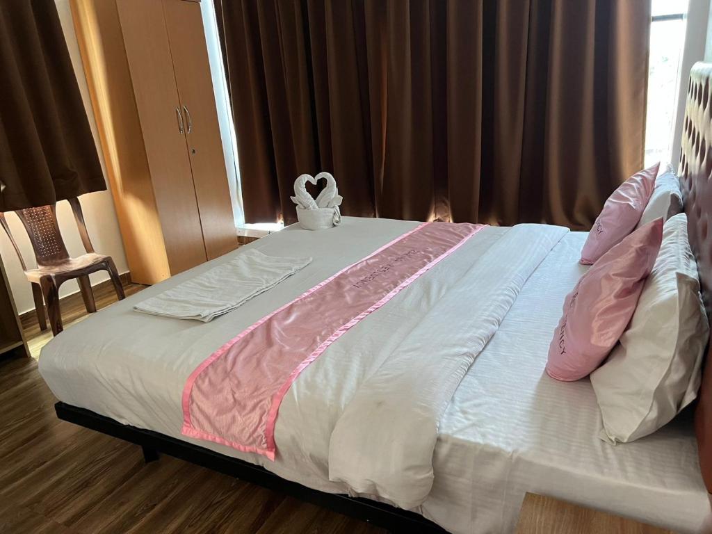 Cama grande con sábanas y almohadas rosas y blancas en Hotel Karna Residency , Ranjangaon, en Ranjangaon