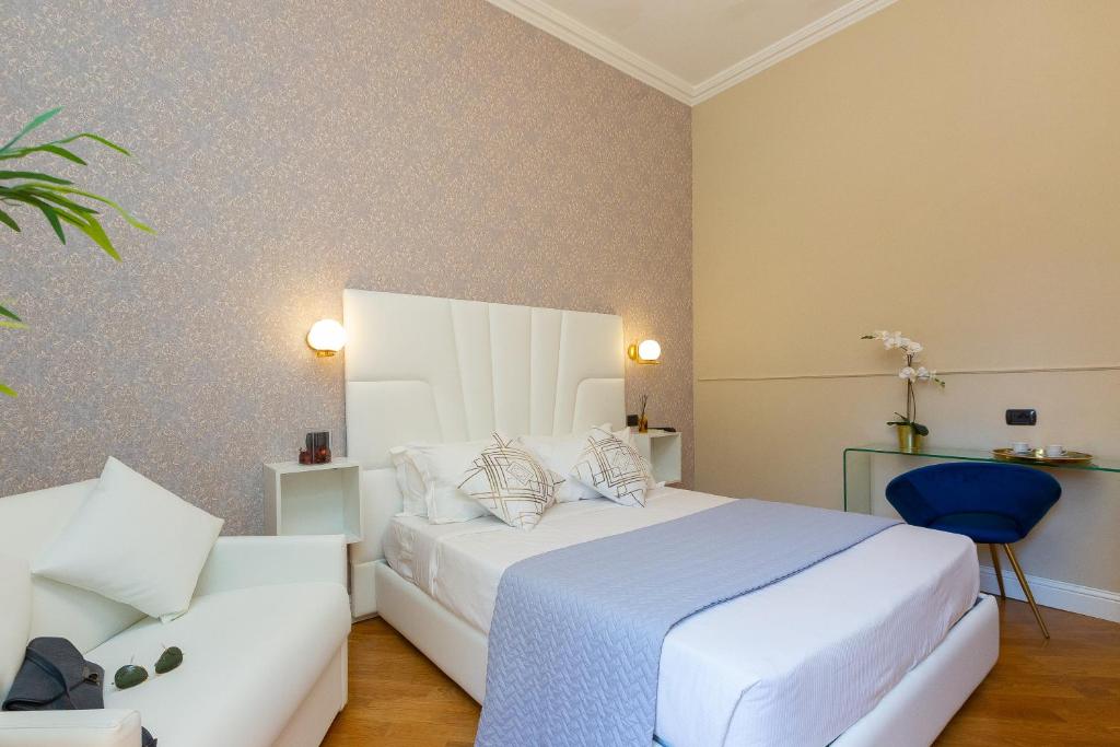 um quarto com uma cama branca e uma cadeira azul em 52 Vespasiano Vatican Suites em Roma