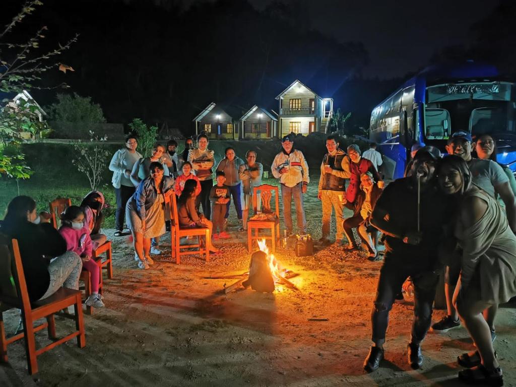 Un groupe de personnes debout autour d'un feu la nuit dans l'établissement Cabañas camino real, à Santiago