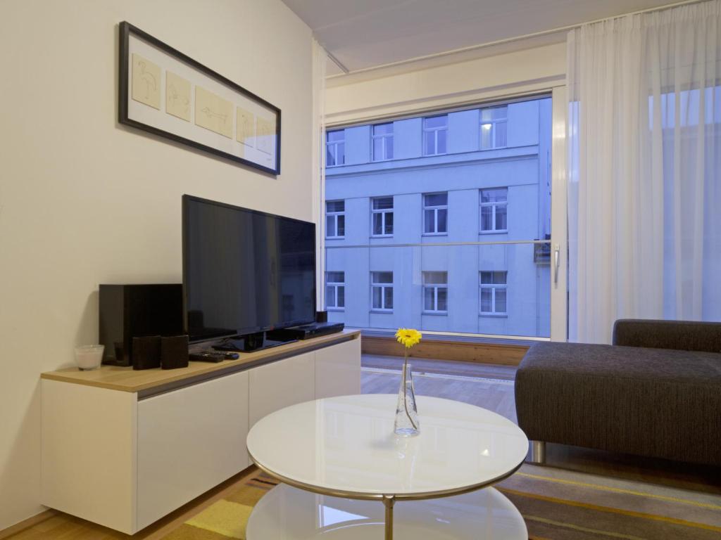 salon z telewizorem i stołem z kwiatem w obiekcie Balcony Dream Mariahilf Top 29 w Wiedniu