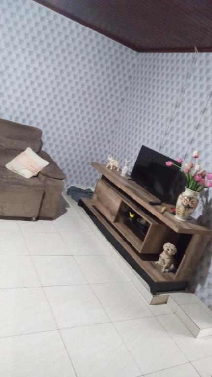 een kamer met een tv en een tafel met bloemen bij AMPLA CASA CONFORTAVEL NO GUARUJA CASCAVEL in Cascavel