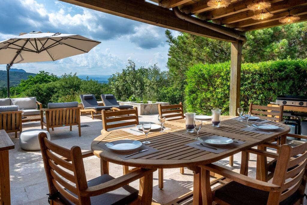 - une table en bois avec des chaises et un parasol sur la terrasse dans l'établissement Esprit du Sud Les 4 Mousquetaires, à Roquebrune-sur Argens