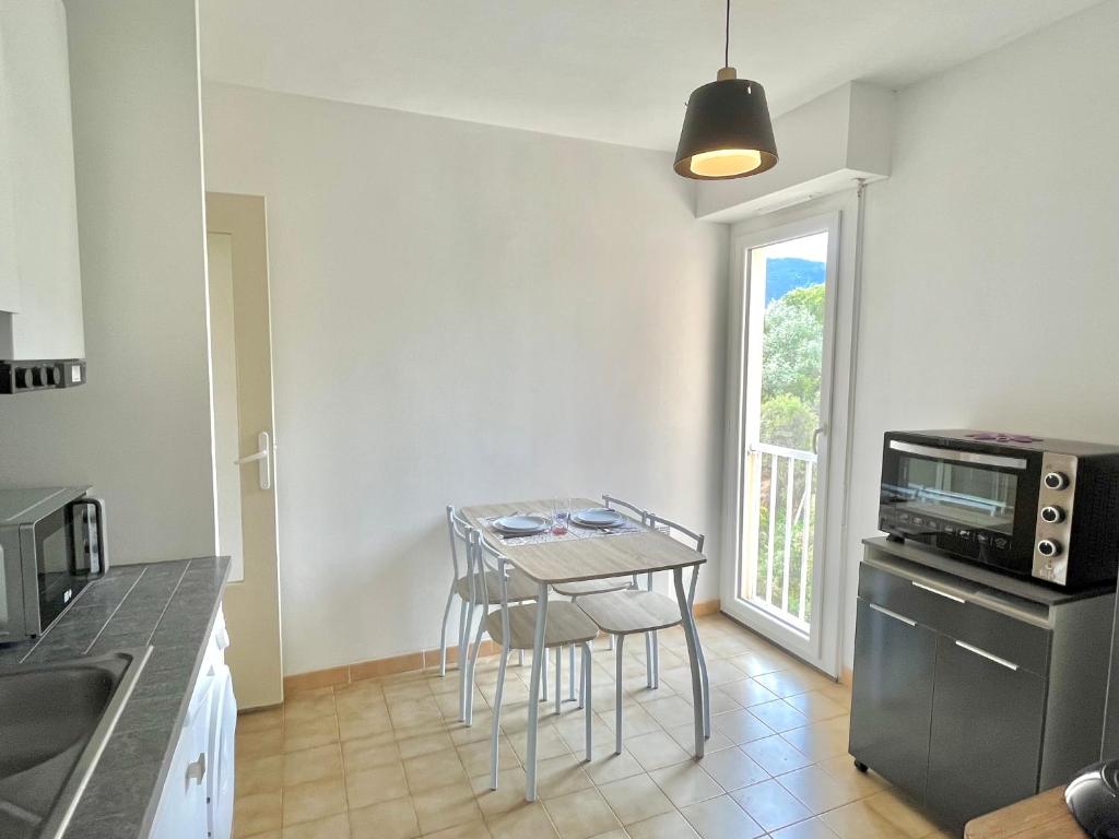 une cuisine avec une table et une petite table avec des chaises dans l'établissement Studio l'orée du bois AJACCIO, à Ajaccio